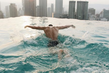 a man swimming in a pool with a city in the background