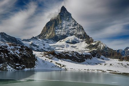 a mountain with snow and a lake